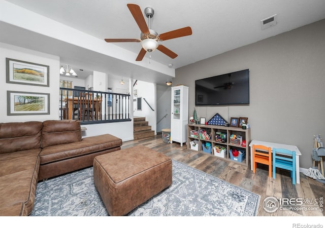 living room with ceiling fan with notable chandelier and hardwood / wood-style flooring