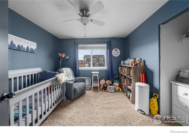 carpeted bedroom with ceiling fan and a crib