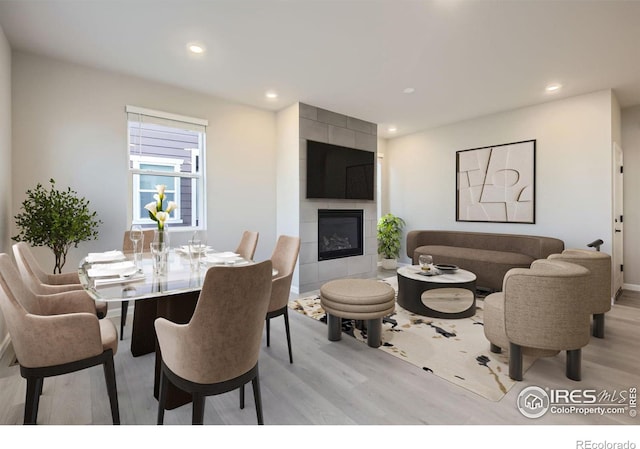 dining room with light hardwood / wood-style floors and a tile fireplace