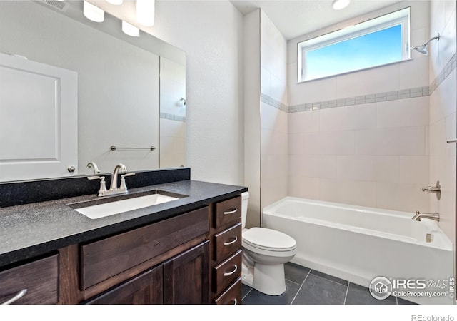 full bathroom featuring toilet, tiled shower / bath combo, vanity, and tile patterned floors