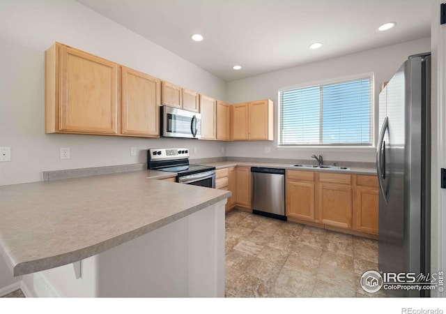 kitchen featuring kitchen peninsula, light brown cabinetry, appliances with stainless steel finishes, and sink