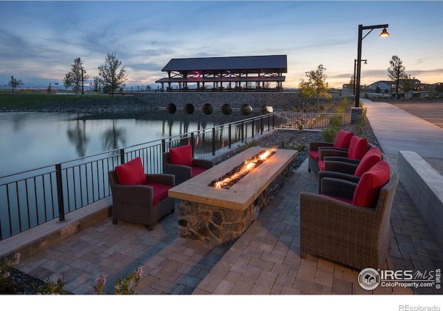 patio terrace at dusk with an outdoor fire pit and a water view