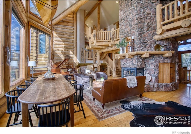 interior space featuring high vaulted ceiling, wood-type flooring, log walls, and a fireplace