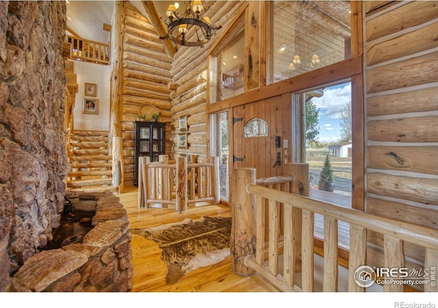 foyer featuring a towering ceiling, rustic walls, a chandelier, and hardwood / wood-style flooring