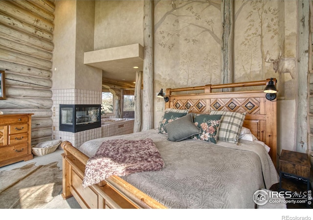 bedroom with a high ceiling, a tile fireplace, log walls, and light carpet