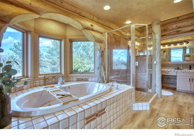 bathroom featuring vanity, wood-type flooring, rustic walls, and a wealth of natural light