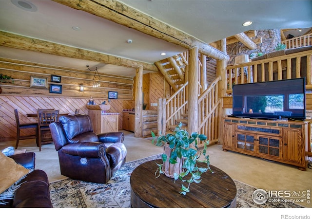 carpeted living room with log walls, a chandelier, wooden walls, and beamed ceiling