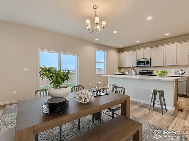 dining area featuring sink, light hardwood / wood-style flooring, and a notable chandelier