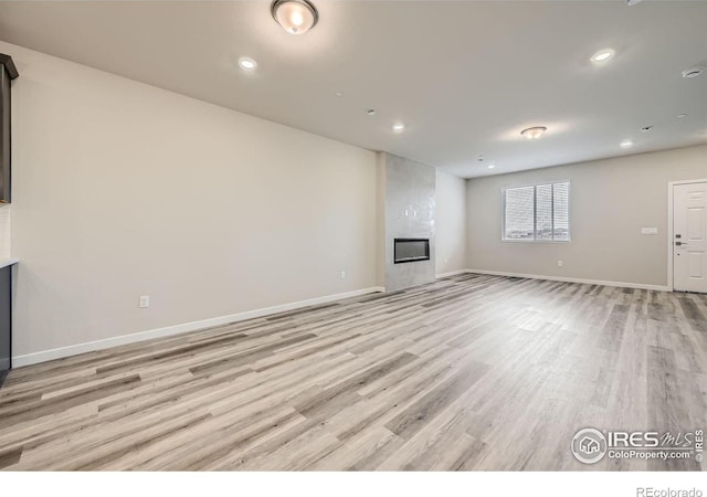 unfurnished living room with a large fireplace and light wood-type flooring