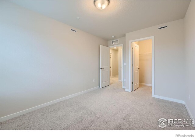 unfurnished bedroom featuring light colored carpet, a spacious closet, and a closet