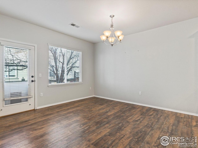 unfurnished dining area featuring an inviting chandelier and dark hardwood / wood-style floors