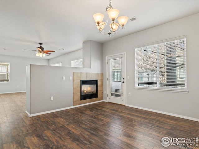 unfurnished living room featuring ceiling fan with notable chandelier, a fireplace, and dark hardwood / wood-style floors