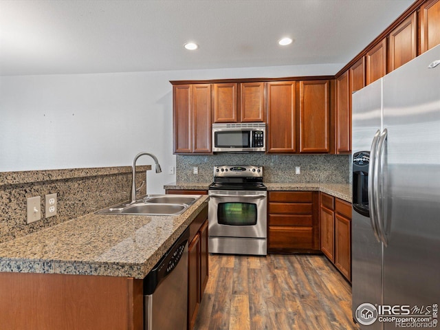 kitchen with appliances with stainless steel finishes, dark hardwood / wood-style floors, backsplash, and sink