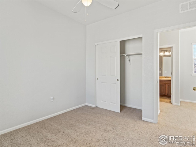 unfurnished bedroom with ceiling fan, light colored carpet, and a closet