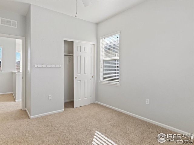 unfurnished bedroom with a closet, ceiling fan, and light carpet