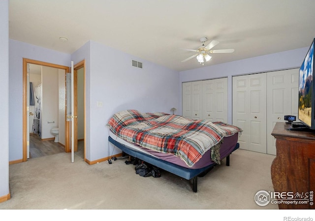 bedroom with connected bathroom, carpet floors, ceiling fan, and two closets