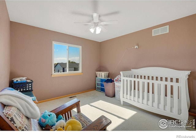 carpeted bedroom featuring a crib and ceiling fan