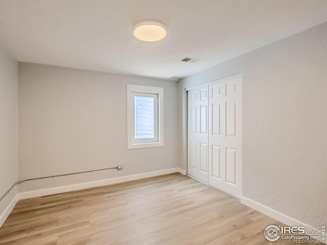 unfurnished bedroom featuring light wood-type flooring and a closet