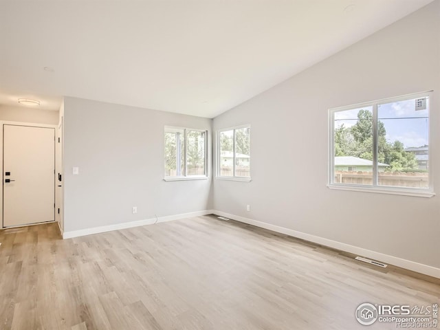 unfurnished room featuring lofted ceiling and light hardwood / wood-style floors