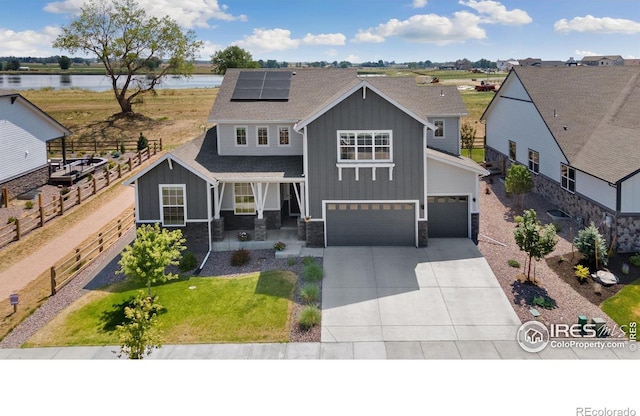 view of front of home with a garage, solar panels, and a water view