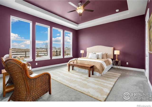 bedroom featuring a tray ceiling, ceiling fan, and light carpet