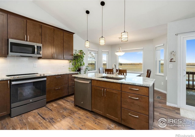 kitchen featuring light stone counters, decorative light fixtures, decorative backsplash, appliances with stainless steel finishes, and sink