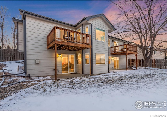 snow covered property with a balcony and a deck