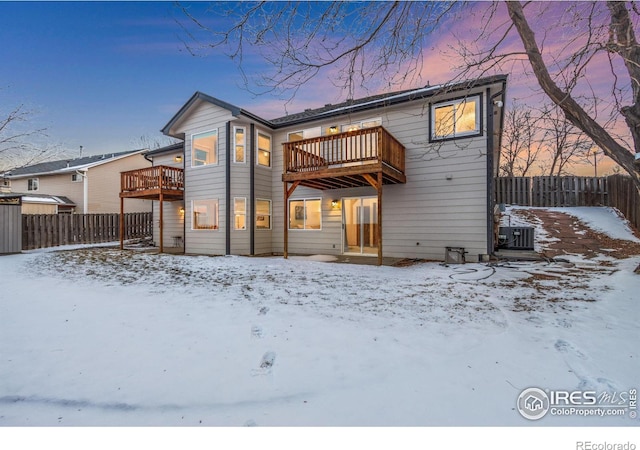 snow covered back of property featuring a balcony and central AC