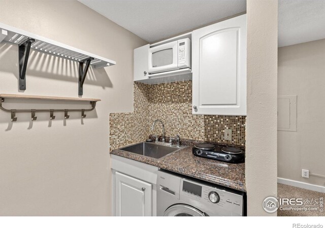 kitchen with washer / dryer, white cabinets, and sink