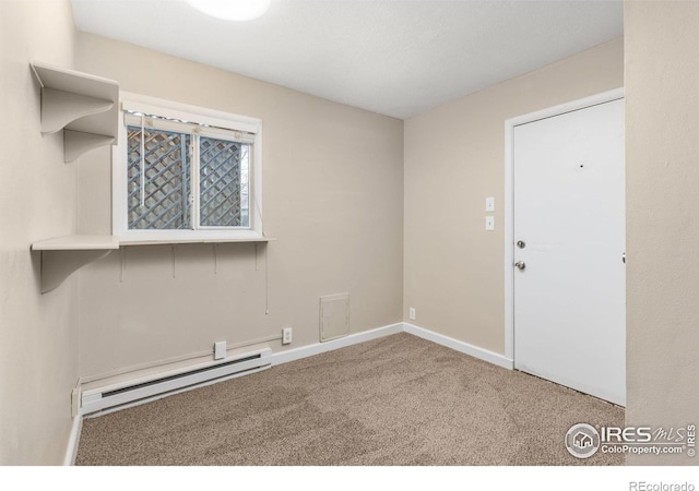 carpeted spare room with a baseboard heating unit