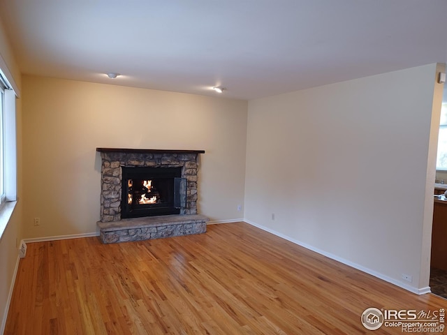 unfurnished living room with a stone fireplace and hardwood / wood-style floors