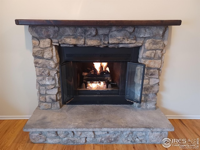 room details featuring hardwood / wood-style floors and a stone fireplace