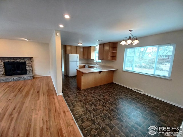 kitchen with kitchen peninsula, white fridge, decorative light fixtures, a breakfast bar, and sink