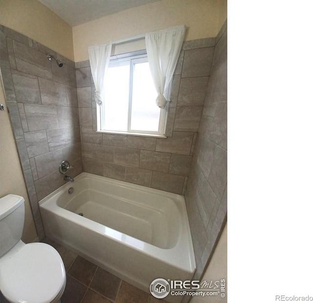 bathroom with tile patterned flooring, toilet, and tiled shower / bath