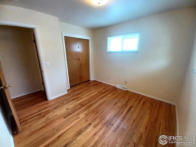 unfurnished bedroom with light wood-type flooring and a closet