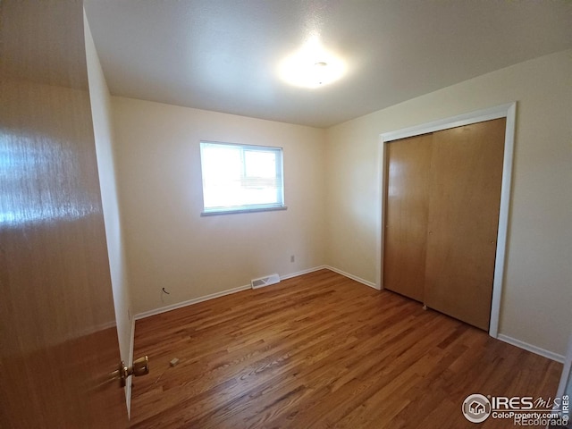 unfurnished bedroom featuring a closet and hardwood / wood-style floors