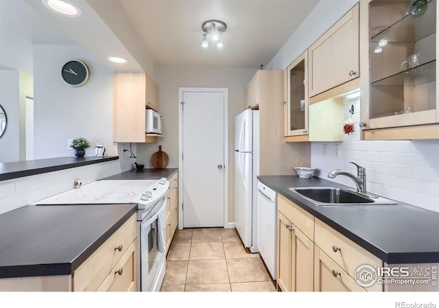 kitchen with white appliances, kitchen peninsula, light tile patterned floors, sink, and backsplash