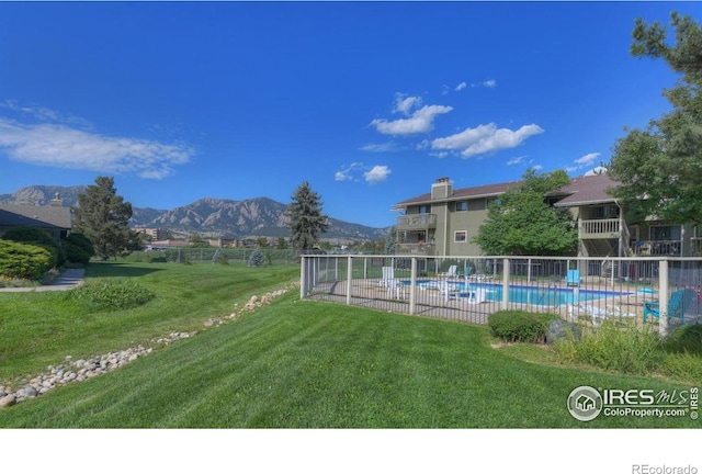 view of swimming pool with a mountain view and a lawn