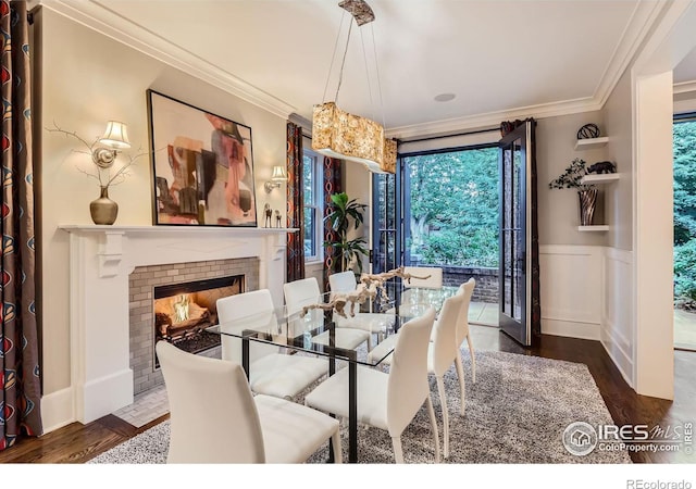 dining area with a brick fireplace, crown molding, and dark wood-type flooring