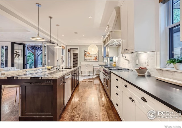 kitchen with decorative light fixtures, dark stone countertops, a spacious island, a breakfast bar, and appliances with stainless steel finishes