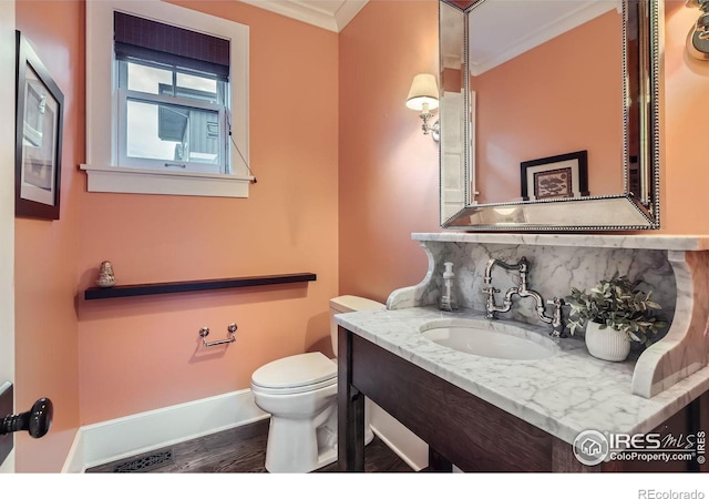 bathroom with hardwood / wood-style floors, toilet, crown molding, vanity, and backsplash