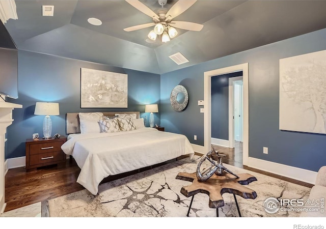 bedroom featuring vaulted ceiling, a raised ceiling, ceiling fan, and hardwood / wood-style floors