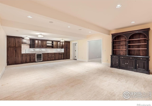 unfurnished living room featuring sink, light colored carpet, and beverage cooler