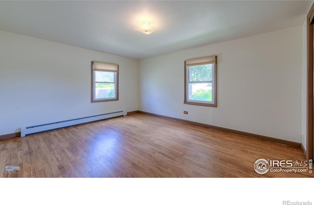 spare room featuring baseboard heating and light wood-type flooring