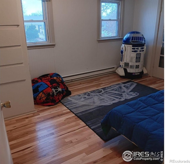 bedroom with a baseboard heating unit and hardwood / wood-style floors