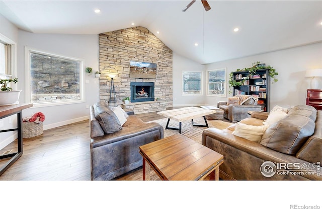 living room featuring ceiling fan, a stone fireplace, vaulted ceiling, and hardwood / wood-style flooring