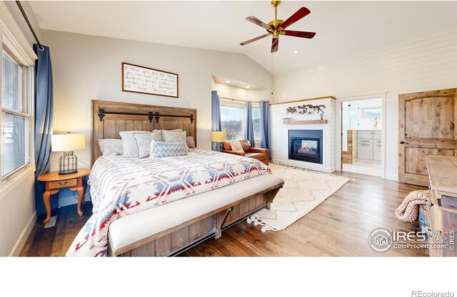 bedroom with ensuite bathroom, hardwood / wood-style floors, ceiling fan, and vaulted ceiling