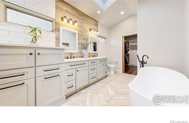 bathroom featuring toilet, parquet floors, a tub, vanity, and lofted ceiling with skylight