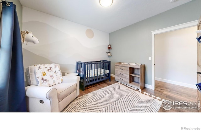 bedroom featuring wood-type flooring and a nursery area