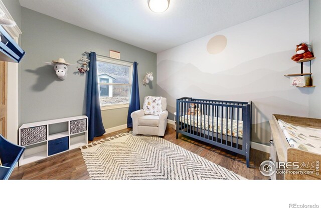 bedroom with a nursery area and wood-type flooring